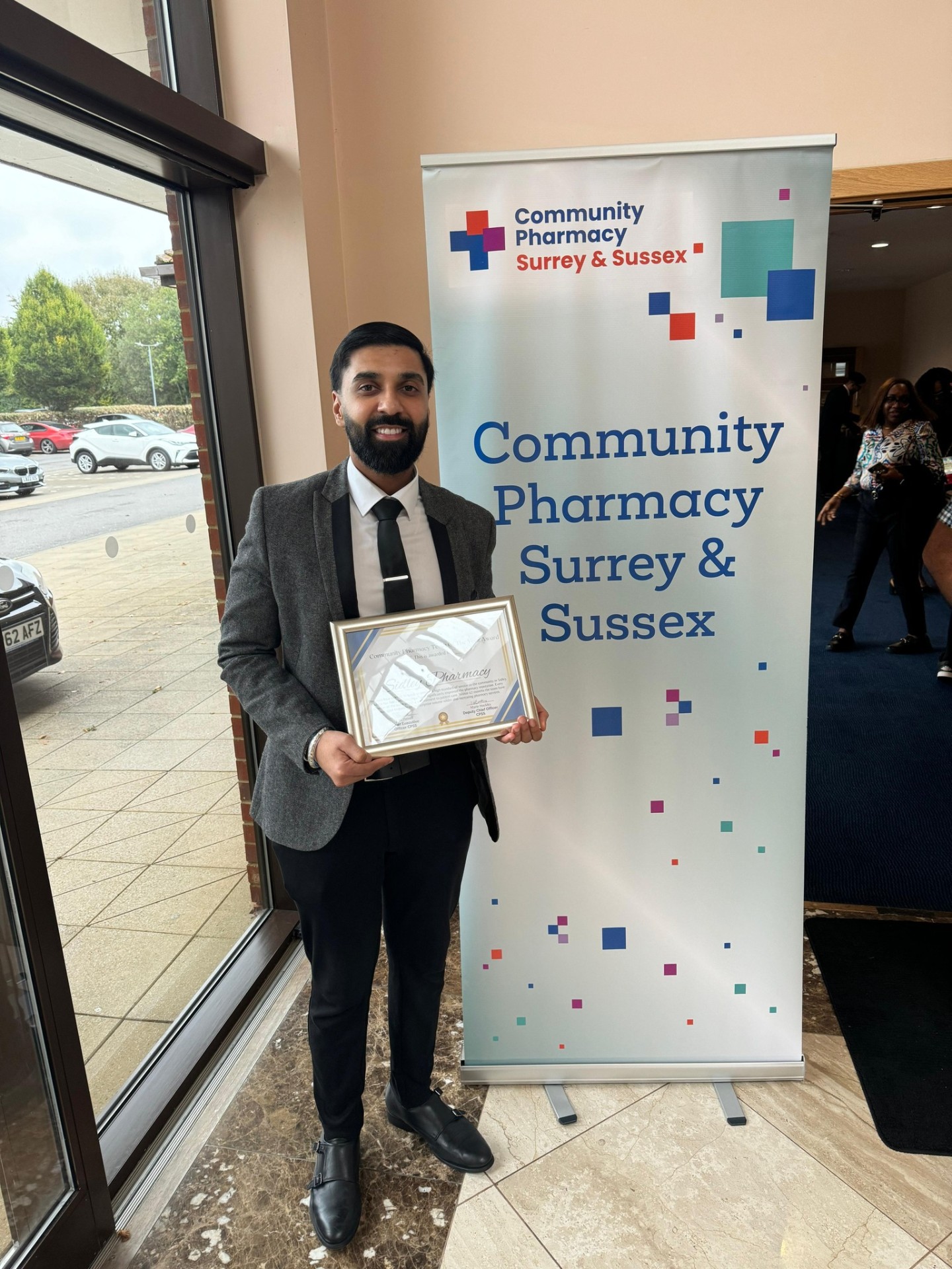 Sukhy Uppal holding Community Pharmacy award certificate